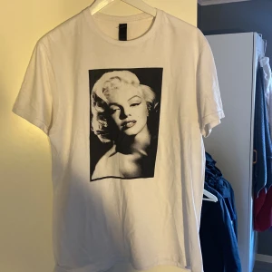 Vit t-shirt med tryck - Säljer en vit t-shirt med ett stort svartvitt tryck på framsidan. T-shirten är kortärmad och i bra skick. Perfekt för en avslappnad stil. Passar till både jeans och shorts! Inga defekter 👍🏼