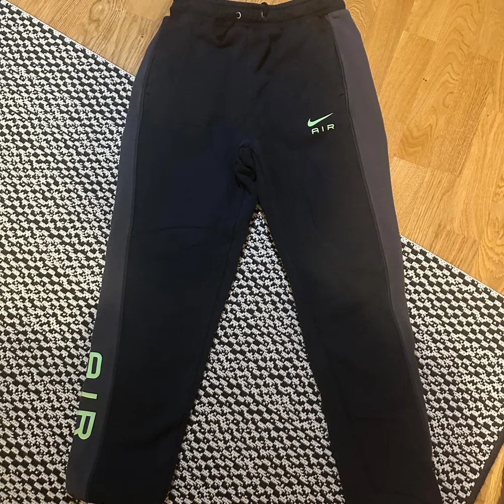 Säljer ett par svarta mjukisbyxor från Nike i storlek S. Byxorna har en grön Nike Air-logga på benet och är perfekta för träning eller chill. De är gjorda i ett mjukt material och har en bekväm passform med dragsko i midjan.. Jeans & Byxor.