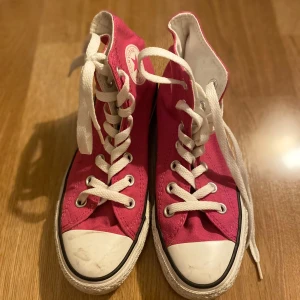 Rosa Converse sneakers - Säljer ett par klassiska rosa Converse sneakers i bra skick. De har vit snörning och den ikoniska vita tåhättan. Perfekta för vår och sommar, och de ger en cool touch till vilken outfit som helst. 