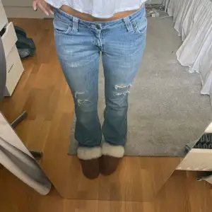 Säljer ett par snygga blå bootcut jeans i bra skick. De är lågmidjade och har slitna detaljer på framsidan, Perfekta för både vardag och fest! Säljer då den är lite för korta för mig som är 1.70