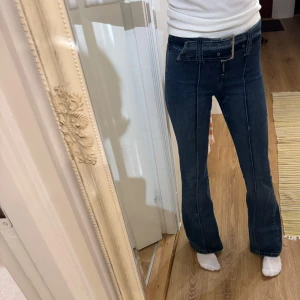 Mörkblå low waist bootcut jeans - Säljer ett par snygga mörkblå low/mid waist bootcut jeans i mycket bra skick. De är högmidjade och har en klassisk femficksdesign med en dragkedja och knappar framtill. Perfekta för både vardag och fest! Knappt använda! 🤍