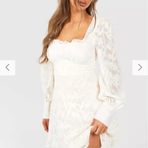 Off white klänning med långa ärmar - Superfin off white klänning med långa ärmar och ett subtilt mönster. Den har en söt volangdetalj vid halsringningen och en smickrande passform. Perfekt för vår och sommar, kanske till en fest, midsommarfirande eller till studenten. Klänningen har en elegant och romantisk stil.