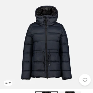 Svart pufferjacka med huva - Säljer en snygg mörbklå pufferjacka med huva. Jackan har en justerbar midja för perfekt passform. Supersnygg och varm! Perfekt för kalla vinterdagar!  Nypris 1000.