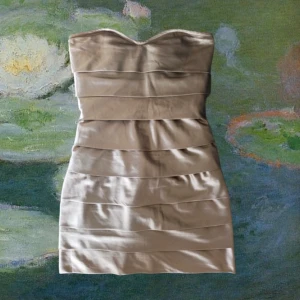 Champagnefärgad klänning från Carryformal - Snygg champagnefärgad klänning från Carryformal i silkes material. Den är axelbandslös och har en dragkedja På ryggen