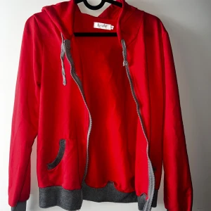 Röd huvtröja från Vicabo - Säljer en snygg röd huvtröja från Vicabo i storlek S. Tröjan har en dragkedja framtill och gråa detaljer vid fickor och muddar. Perfekt för en avslappnad stil och passar bra till både höst och vår. Huvtröjan är i bra skick och redo för nya äventyr! 🔥