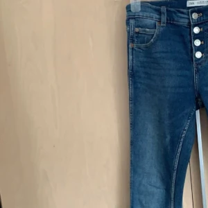 Blå bootcut lowayst jeans från Zara - Säljer ett par snygga blå bootcut jeans från Zara. De har en låg midja och knappar framtill. Perfekta för både vardag och fest! 🦋Säljer eftersom de var försmå❣️