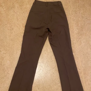 Bruna kostymbyxor - Säljer ett par bruna kostymbyxor i mycket bra skick. De har en straight passform. Byxorna har en hög midja och stängs med dragkedja och knapp. Passar perfekt till höst- och vintergarderoben. ❤️💕