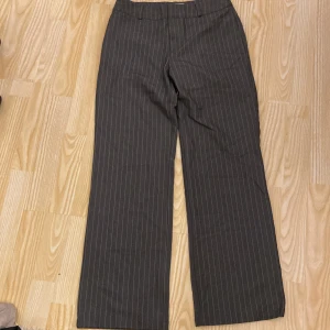 Grå randiga kostymbyxor💞 - Säljer ett par snygga grå randiga byxor från Madlady i storlek EU 34/Short. De har en klassisk och stilren look med en rak passform. 