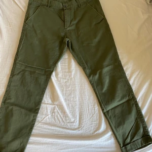 Gröna byxor från Dr. Denim - Säljer ett par gröna byxor från Dr. Denim i storlek 33/34. De är i mycket bra skick och gjorda av 100% bomull. Perfekta för höst och vår med en normal passform och stilren design. Byxorna har knappar och dragkedja framtill samt fickor både fram och bak. Liten ljus fläck på ena benet som evt går bort i tvätten.
