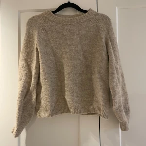 Beige stickad tröja från VILA - Mysig beige stickad tröja från VILA i storlek S. Tröjan har långa ärmar och en klassisk rund halsringning. 