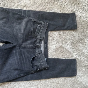 Grå/Svarta jeans från Replay - Snygga grå/svarta jeans från Replay med en slim passform. De har en klassisk femficksdesign och en diskret Replay-logga på bakfickan. Perfekta för en stilren look. Storlek 16 år alltså största barnmodell. Lite stora för mig som är 175 cm. Fåtal gånger använda. Bara att höra av dig vid frågor.