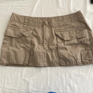 Beige kortkjol med fickor - Snygg beige kortkjol med praktiska fickor framtill och en knappstängning. Perfekt för en avslappnad stil. Kjolen har en klassisk design som passar till många olika tillfällen. Jag har sytt in kjolen så att den ska vara kortare