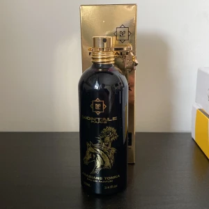 Arabians Tonka Eau de Parfum från Montale - Elegant parfymflaska i svart med guldtryck och en hästdesign. Flaskan rymmer 100 ml av doften Arabians Tonka, känd för sina rika och orientaliska toner. Förpackningen är i glänsande guld, vilket ger en lyxig känsla. Perfekt för den som älskar djupa och varma dofter.