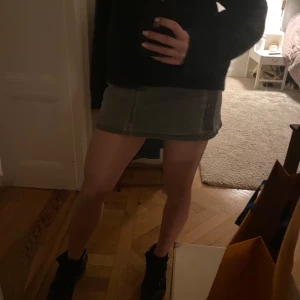 Grå jeanskjol med paljettdetaljer - Snygg grå manchesterkjol med paljettdetaljer på fickorna. Kjolen har en klassisk design med knapp och dragkedja framtill. Perfekt för att ge en touch av stil till din outfit.