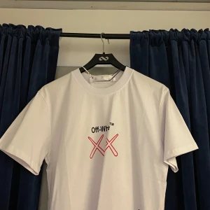 Vit t-shirt från Off-White - Snygg vit t-shirt från Off-White med ett coolt tryck på baksidan och ett enkelt motiv på framsidan. Perfekt för dig som vill ha något unikt i garderoben. T-shirten har korta ärmar och är gjord i bomull. Aldrig använd prislapp o sött sitter i på nypris 4349kr