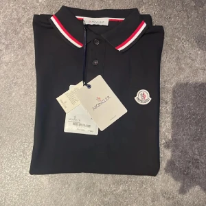 Svart pikétröja från Moncler - Snygg svart pikétröja från Moncler med tags o allt! Tveka inte på o höra av dig!🤝