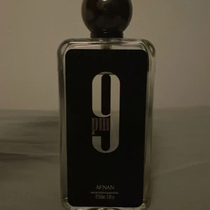 9 PM Eau de Parfum från Afnan - Säljer en elegant flaska av 9 PM Eau de Parfum från Afnan. Flaskan är rektangulär med en svart etikett och en stilren design. Den har en mörk rund kork som ger ett lyxigt intryck. Perfekt för kvällsbruk med en sofistikerad doftprofil. Nypris 380 kr de är 90 ml kvar använt typ ingenting