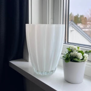 Vit vas med vågig kant - Elegant vit vas med en unik vågig kantdesign. Perfekt för att ge ditt hem en stilren touch. Passar utmärkt för både blommor och som en dekorativ pjäs i sig själv. Säljs pga att jag inte har användning för den 🩵