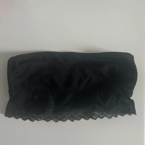 Svart tubtopp med spetsdetaljer - Snygg svart tubtopp med vacker spetskant nedtill. Perfekt för att lägga till en touch av elegans till din outfit. Enkel och stilren design. Funkar som liten topp eller bh💓