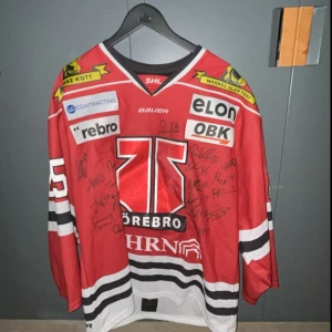 Äkta Örebro hockey tröja - Säljer en helt äkta Örebro hockey tröja i hemmatställ. Den är ifrån Maksims Semjonovs. Den har även alla autografer på ifrån Örebro hockey