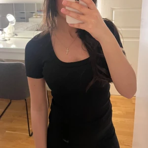 Svart ribbad t-shirt - Säljer en stilren svart ribbad topp med korta ärmar. Perfekt för en enkel och snygg look. Toppen har en rund halsringning och är i en tight passform.