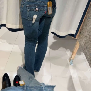 Blå jeans från Levi's - Säljer ett par klassiska blå jeans från Levi's med fem fickor och knappgylf. De har en traditionell passform och är perfekta för en avslappnad stil. Levi's-loggan syns tydligt på bakfickan.