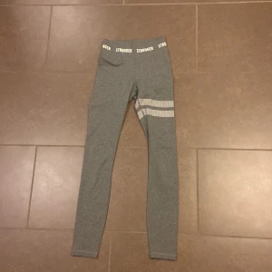 Grå leggings från Stronger - Snygga grå leggings från Stronger i storlek xxs. De har vita prickar på ena låret och använda få gånger💕