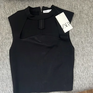 Svart ärmlös topp från Zara - Snygg svart ärmlös topp från Zara med urringad hals med choker. Aldrig använd med prislapp kvar. Storlek L men är väldigt liten i storlek så skulle nog säga att den passar allt från xs till M.  Kontakta för mer info💞💞