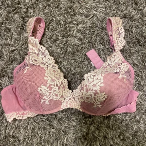 Rosa Intimissimi spets-bh - Säljer en vacker rosa bh med spetsdetaljer i vitt. Bh:n har justerbara axelband och en elegant design med blommönster. Perfekt för att känna sig extra fin.