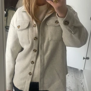 Beige overshirt med knappar - Säljer en stilren beige overshirt med knappar framtill och två bröstfickor. Passar både till vardags och mer uppklädda tillfällen. Använd fåtal gånger! 💖
