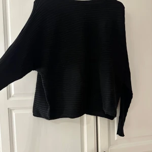 Svart ribbad tröja från KappAhl - Säljer en stilren svart ribbad tröja från KappAhl. Tröjan har en klassisk design med långa ärmar och rund halsringning. 