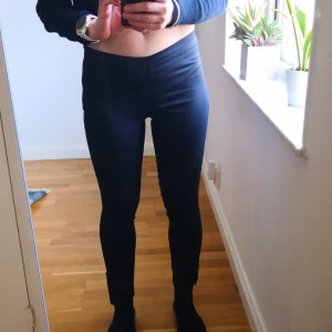 Mörkblå/Midnattsblå leggings/byxor slim fit från Designers Remix  - Mörkblå/Midnattsblå leggings/byxor från Designers Remix med en tight passform. Perfekta för en stilren look och kan enkelt matchas med olika toppar. De är bekväma och stretchiga, vilket gör dem idealiska för både vardag och mer avslappnade tillfällen. Dragkedja i sidan, och nertill i byxbenen. Storlek 26. 