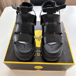 Svarta sandaler från Buffalo - Snygga svarta sandaler från Buffalo med robust sula och justerbara remmar. Perfekta för en trendig look med sin chunky design. Tillverkade i veganskt material och kommer i originalförpackning.