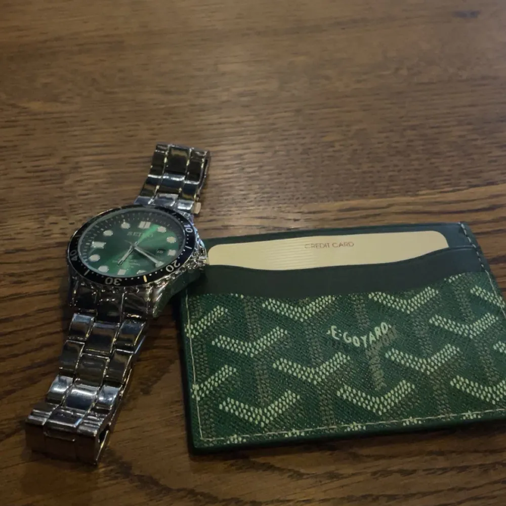 Säljer en stilren dykarklocka från Seiko med grön urtavla och datumvisning. Klockan har en robust silverfärgad länkarmband och tydliga markeringar på bezeln. Perfekt för både vardag och äventyr under vattnet.. Asusteet.