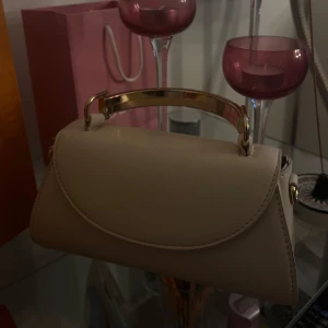 Beige handväska med metallhandtag - Elegant beige handväska med stilrent metallhandtag