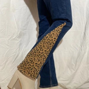 Blå jeans med leoparddetaljer - Unika blå jeans med leopardmönstrade inslag längs benen. Dessa jeans har en klassisk femficksdesign och en dragkedja framtill. Perfekta för dig som vill sticka ut med en djärv stil. Bilder ifrån tidigare säljer