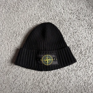 Svart ribbad mössa från Stone Island - Snygg svart mössa från Stone Island, perfekt för att hålla dig varm och stilren under kyliga dagar. Nypris 5000kr. vid snabb affär så kan jag gå ner i pris.