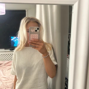 Vit stickad tröja - Säljer en vit stickad tröja med korta ärmar. Tröjan har en avslappnad passform och är perfekt för en stilren look. Den är helt oanvänd men står ej storlek men uppskattas som s-m men skulle även passa L
