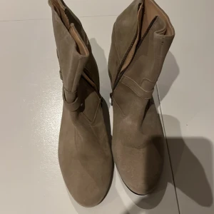 Beige boots från Esprit - Snygga beige boots från Esprit med dragkedja på sidan. Tillverkade i mocka med en låg klack för extra komfort. Perfekta för både vardag och lite finare tillfällen.