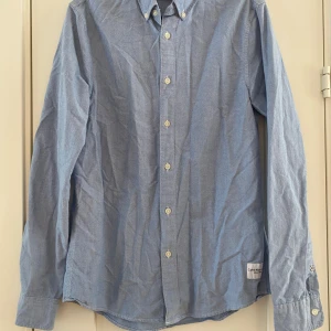Blå skjorta från Calvin Klein Jeans - Snygg blå skjorta från Calvin Klein Jeans i slim fit. Skjortan har långa ärmar och knappar framtill. Perfekt för en stilren look. Ljusblå skjorta i Oxford bomull i strl S från Calvin Klein Jeans, modell slim fit.  Endast använd vid ett par tillfällen och i fint begagnat skick.  Mått Över bröstet: ca 50 cm Längd från axeln och ner: ca 72 cm  100% bomull   Kommer från ett djur och rökfritt hem.