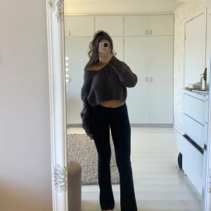 Brun stickad croppad tröja - Säljer en mysig brun stickad tröja med en croppad design. Tröjan har en offshoulder-stil och långa ärmar, perfekt för en avslappnad look. Passar bra till både jeans och kjol.