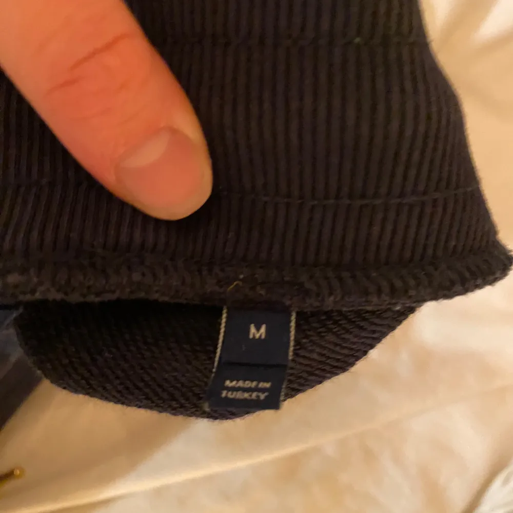 Säljer ett par svarta mjukisbyxor med broderad logga på benet. Byxorna har en bekväm passform med dragsko i midjan för justering. Perfekta för en avslappnad stil.. Farkut & Housut.