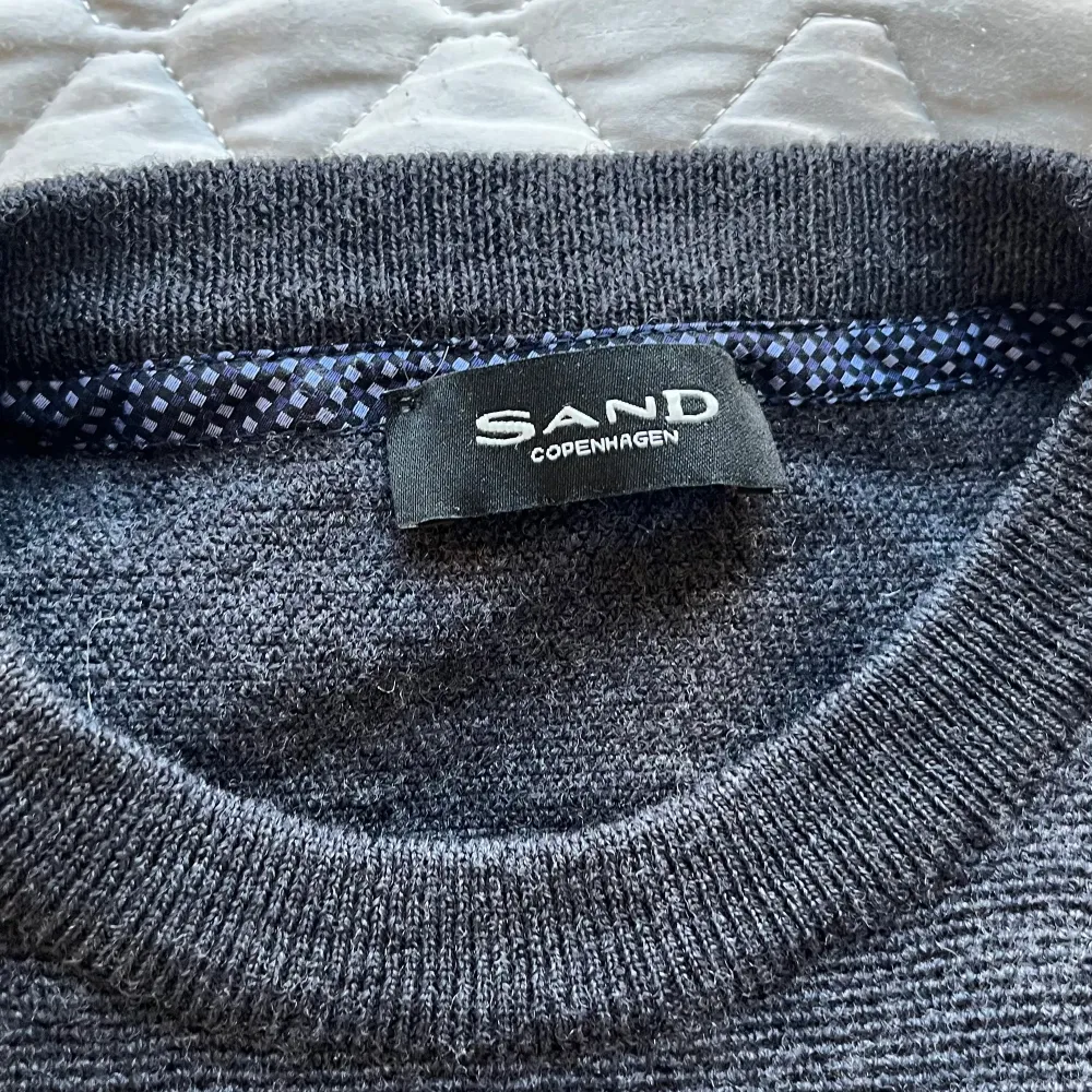 Säljer en stilren mörkgrå tröja från Sand Copenhagen i 100% merinoull. Tröjan har en klassisk design med rund hals och långa ärmar, perfekt för kyligare dagar. Ett måste för garderoben! 🖤den är i mycket gott skick och innehar samma fantastiska kvalitet som alla varor från Sand. Hör gärna av vid frågor, funderingar eller prisförslag:). Neuletakit & Villapaidat.