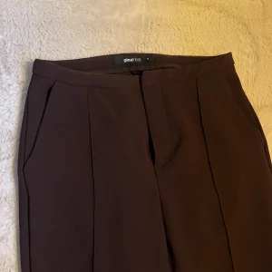 Bruna kostymbyxor från Gina Tricot - Snygga bruna kostymbyxor från Gina Tricot med mid-waist och bootcut! 