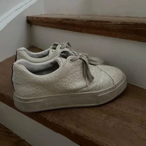 Eytys  - Snygga vita sneakers med snörning och en robust sula. Skorna har en stilren design med en något texturerad yta. Perfekta för en avslappnad stil.