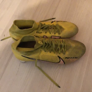 Nike Mercurial Superfly 9 Pro  - Säljer ett par gula Nike fotbollsskor. Skorna har en strumpliknande passform och är designade för optimal prestanda på planen. Perfekta för fotbollsspelare som vill ha stil och funktion. Har fixat   snören till dom då jag har kört laceless med skorna, skicka på dom här är 8,5/10 så de går att fortsätta använda de.