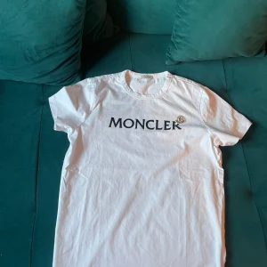 Vit t-shirt från Moncler - Säljer en stilren vit t-shirt från Moncler med deras ikoniska logga tryckt på bröstet. Har knappast användts. Den har inga håll eller fläckar. Alla qr coder och scans funkar.