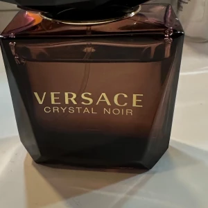 Versace Crystal Noir Eau de Toilette 30 ml , Använd några tillfällen , tyvärr ingen kartong  - Säljer en elegant Versace Crystal Noir Eau de Toilette i en lyxig mörklila flaska med en facetterad svart kork. Flaskan rymmer 30 ml av denna förföriska doft som utstrålar mystik och elegans. Perfekt för den som vill ha en sofistikerad och unik doftupplevelse., Använd fåtal  tillfällen men stort sett mycket kvar att ge , Tyvärr ingen kartong kvar 