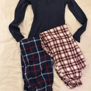 Två par rutiga pyjamasbyxor - Två par mysiga pyjamasbyxor i rutig design. Ett par i blått och rött, och ett par i vinrött och vitt. Perfekta för en avslappnad kväll hemma.