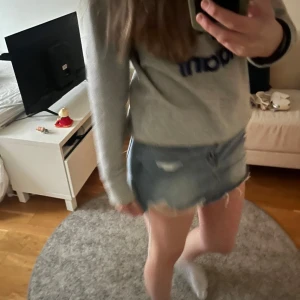 Blå jeanskjol - Säljer en snygg blå jeanskjol med slitna detaljer och rå kant. 